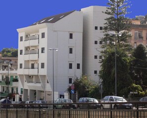 A multi-story building with balconies, a street in front, and parked cars. - Residence Annunziata (Messina)