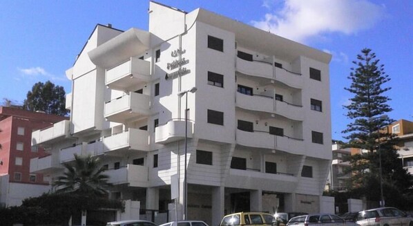 A multi-story building with balconies, a sign reading "Hotel", and several parked cars in front. - Residence Annunziata (Messina)