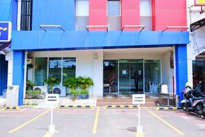 Fachada de un edificio con colores azul y rojo, puertas de vidrio y un letrero que dice 'PARKIR CORDEX'.