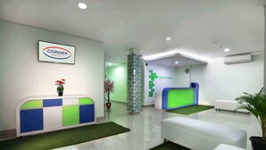 A modern hotel reception area with a reception desk, seating area, and a sign indicating the hotel name. - Cordex Hotel Ancol Jakarta (Jakarta)