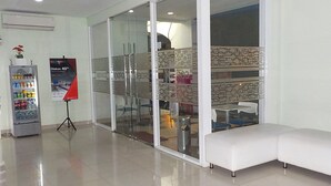 A modern interior with a seating area, a vending machine, and a glass partition with a patterned design. - Cordex Hotel Ancol Jakarta (Jakarta)