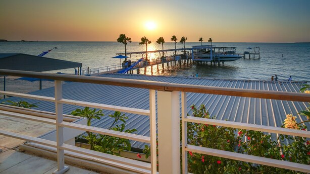 A pier extending into calm waters at sunset, with a railing and potted plants in the foreground. - Ocean View Residence - Hotel Jepara (Jepara)