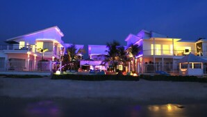 A beachfront property with multiple buildings, including a main house and a smaller structure, illuminated by purple and white lights. - Ocean View Residence - Hotel Jepara (Jepara)