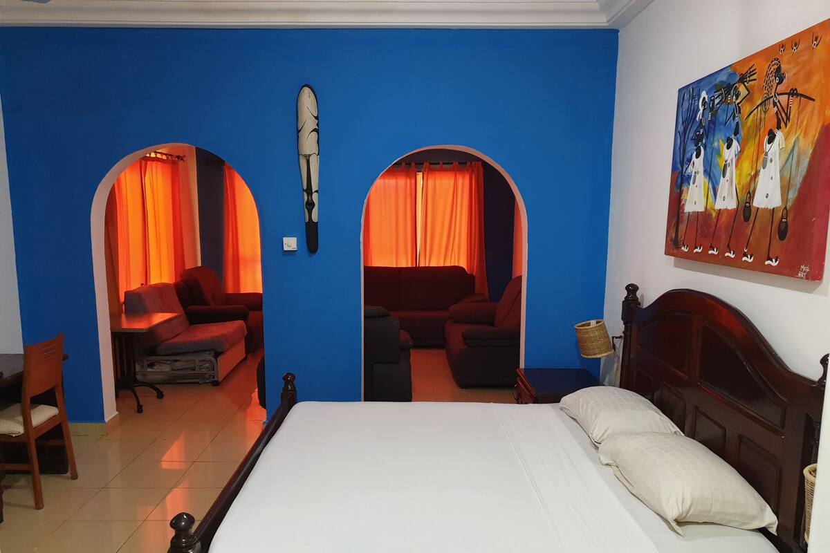 Une chambre d’hôtel avec un grand lit, deux canapés et un tableau au mur.