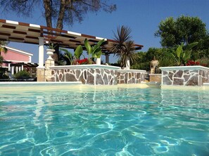 Una piscina al aire libre, sombrillas, sillones reclinables de piscina