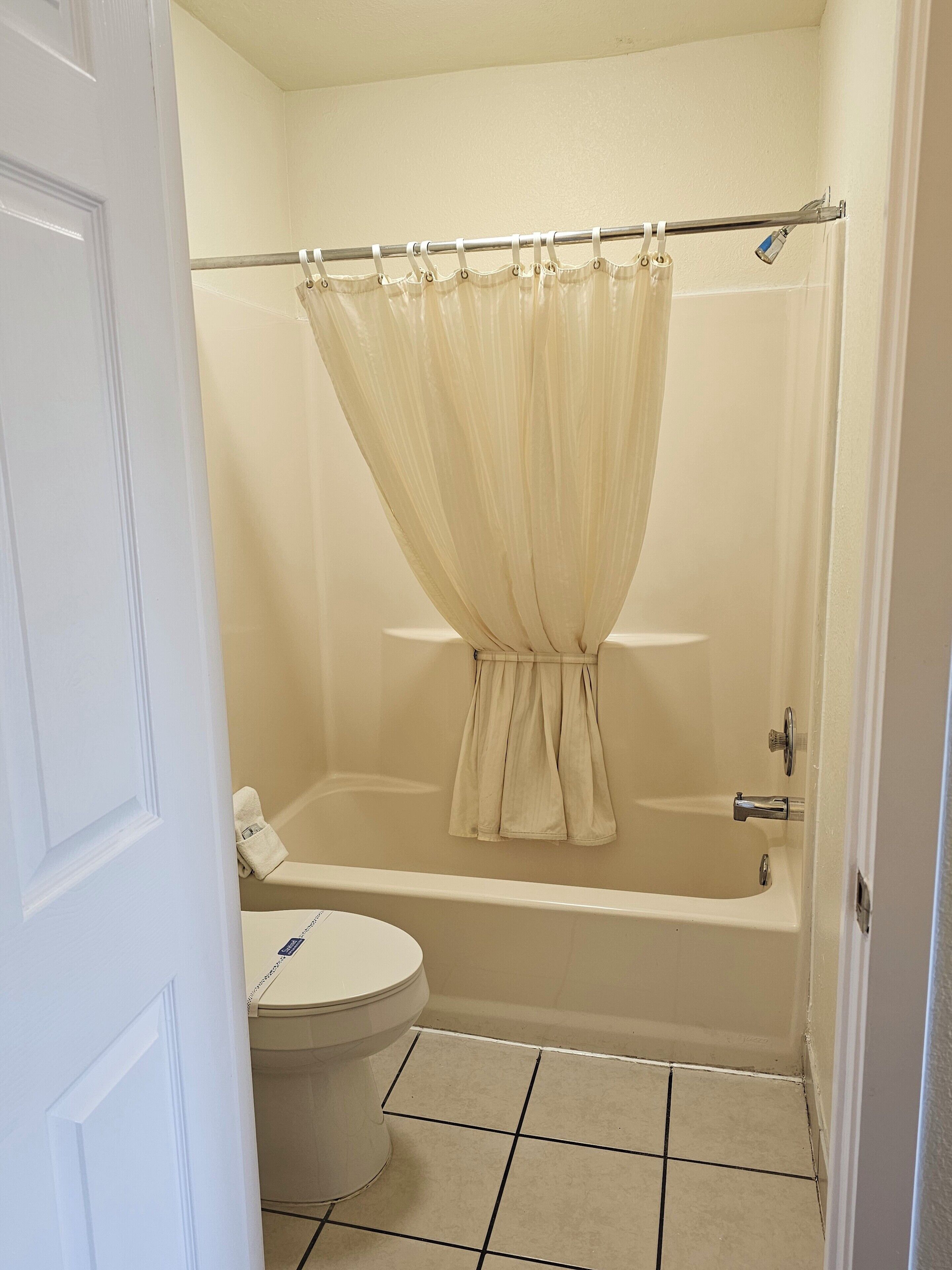 A bathroom with a bathtub, toilet, and a shower curtain.