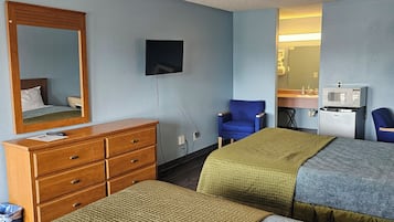 Una habitación de hotel con dos camas, un aparador de madera, televisor, microondas y espejo.