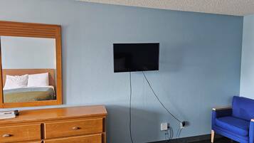 A bedroom with a bed, dresser, TV, and a blue chair.