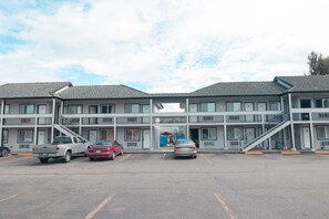 A two-story motel with a central entrance, parking spaces, and a covered outdoor area.