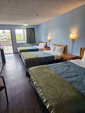 A hotel room with two beds, a desk, and a chair. There are two bedside lamps and a window with curtains.