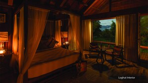 Un lit à baldaquin, une table de chevet avec une lampe, une chaise et une table avec une bouteille et un verre.