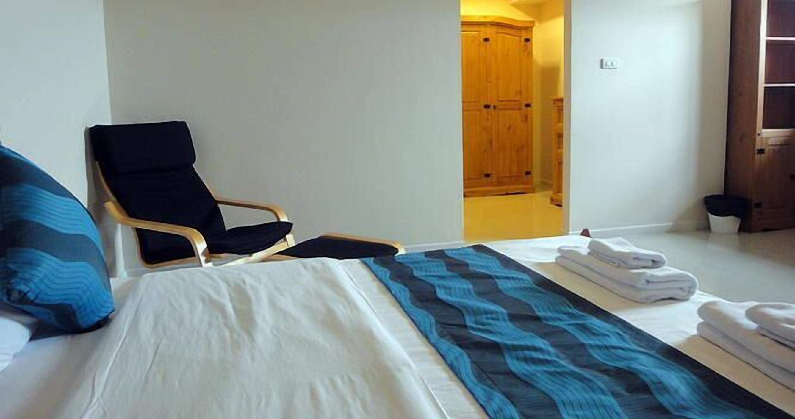 Una habitación de hotel con una cama, una silla y un armario de madera.