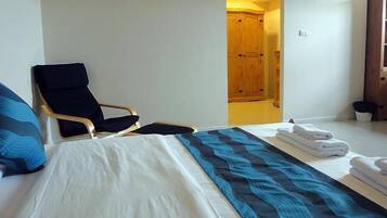 Una habitación de hotel con una cama, una silla y un armario de madera.