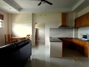 A modern kitchen with wooden cabinets, a built-in microwave, and a ceiling fan.