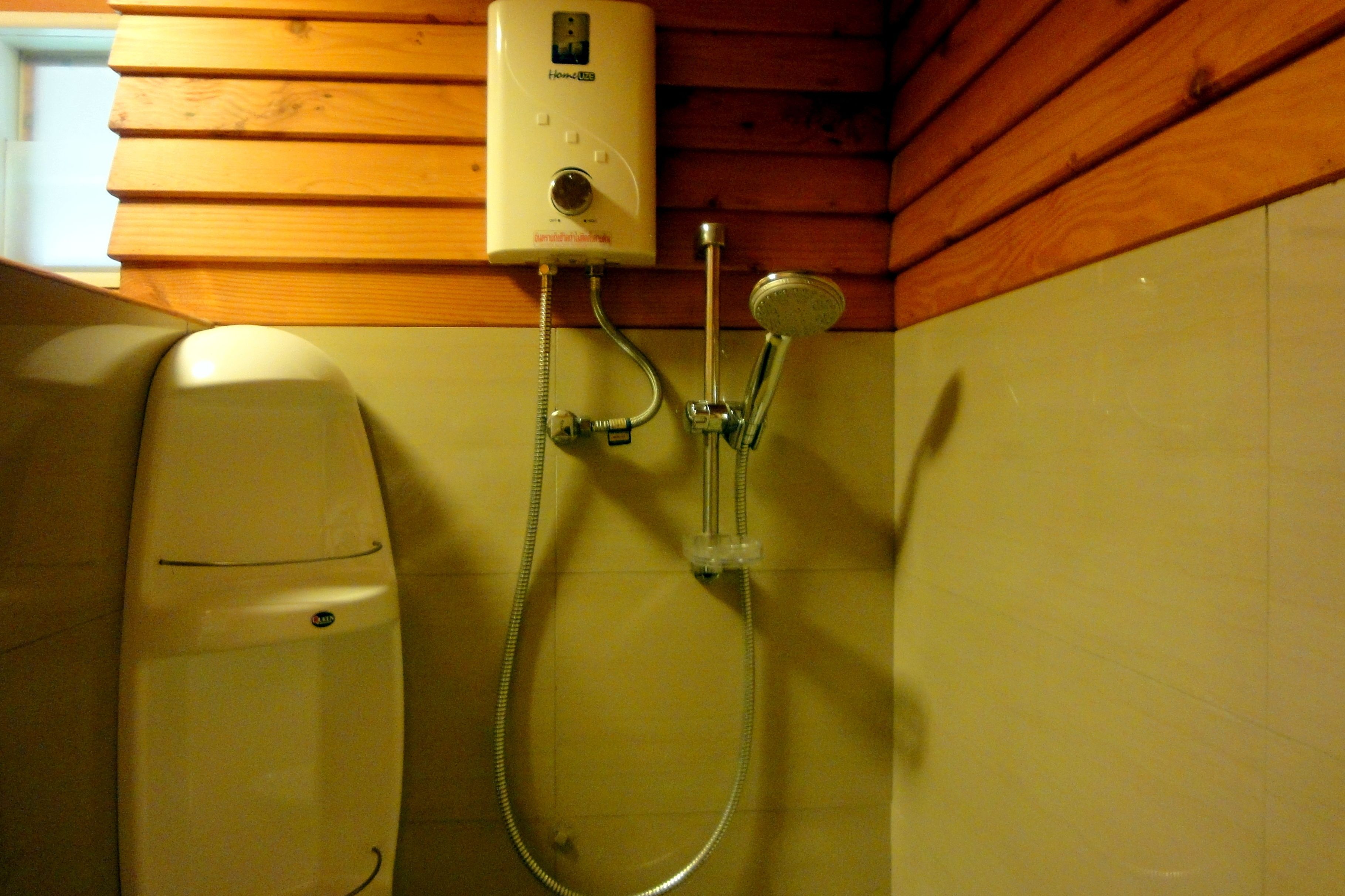 A bathroom with a built-in shower unit, a handheld showerhead, and a wall-mounted faucet.