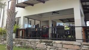 Un edificio moderno con un patio cubierto, pared de piedra y mobiliario exterior.