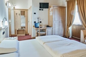 A hotel room with a bed, desk, chair, wardrobe, and a television on the wall. - Albergo 2000 (Livigno)