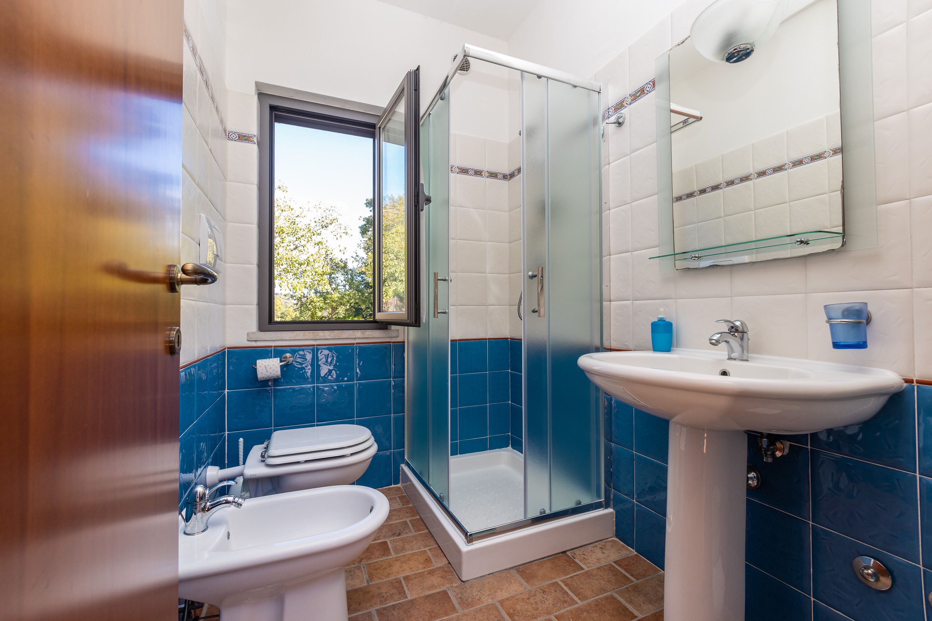 A bathroom with a glass-enclosed shower, a sink, and a toilet.