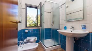 A bathroom with a glass-enclosed shower, a sink, and a toilet.