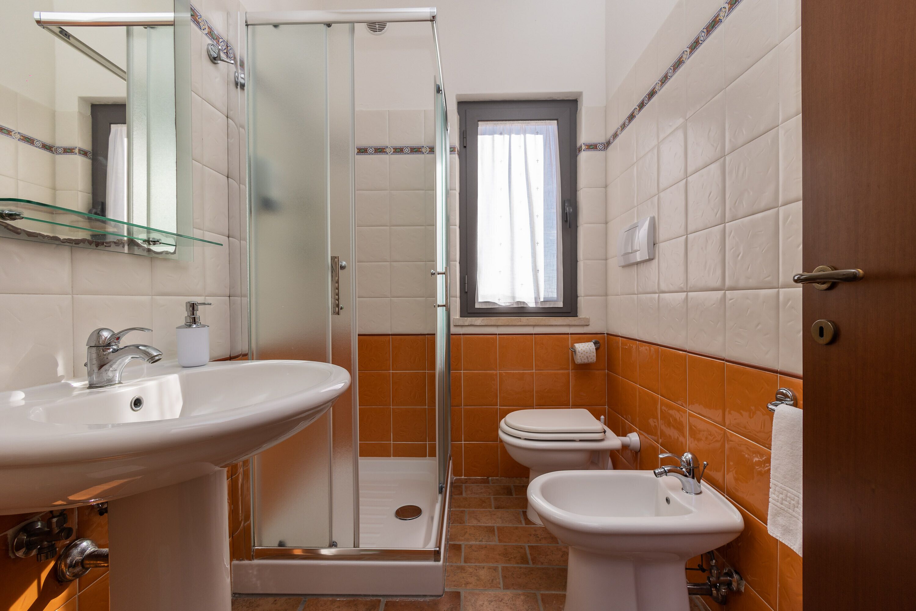 A bathroom with a glass shower enclosure, a sink, and a toilet.