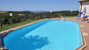 A rectangular pool with a clear blue water surface, surrounded by a tiled deck and a wooden fence.