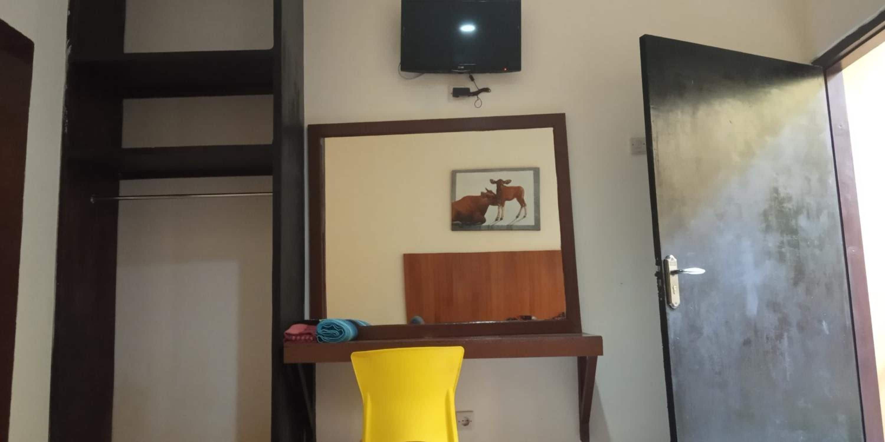 A room with a television mounted on the wall, a door, and a framed picture of a cow.