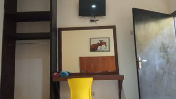 A room with a television mounted on the wall, a door, and a framed picture of a cow.