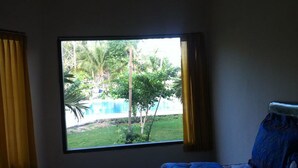 A room with a large window overlooking a pool and greenery. - Vico Hotel (Nusa Dua)