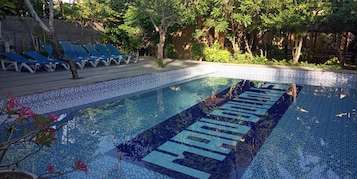 Una piscina con borde de azulejos y superficie de agua cristalina azul.