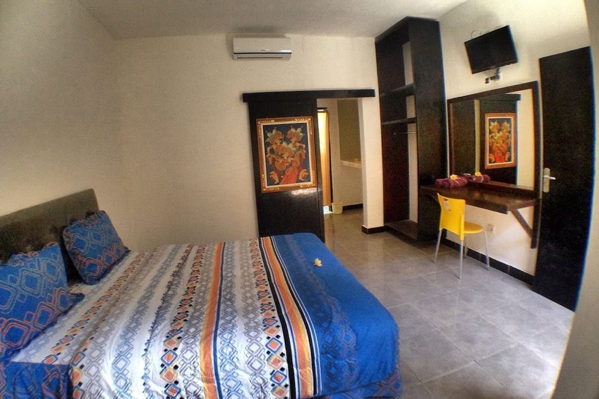 Een slaapkamer met een bed, een bureau, een stoel en een spiegel.