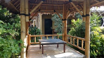 A bamboo structure with a table and benches, surrounded by lush greenery.