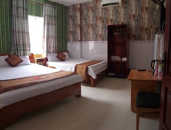 Una habitación de hotel con dos camas, un escritorio y un armario.