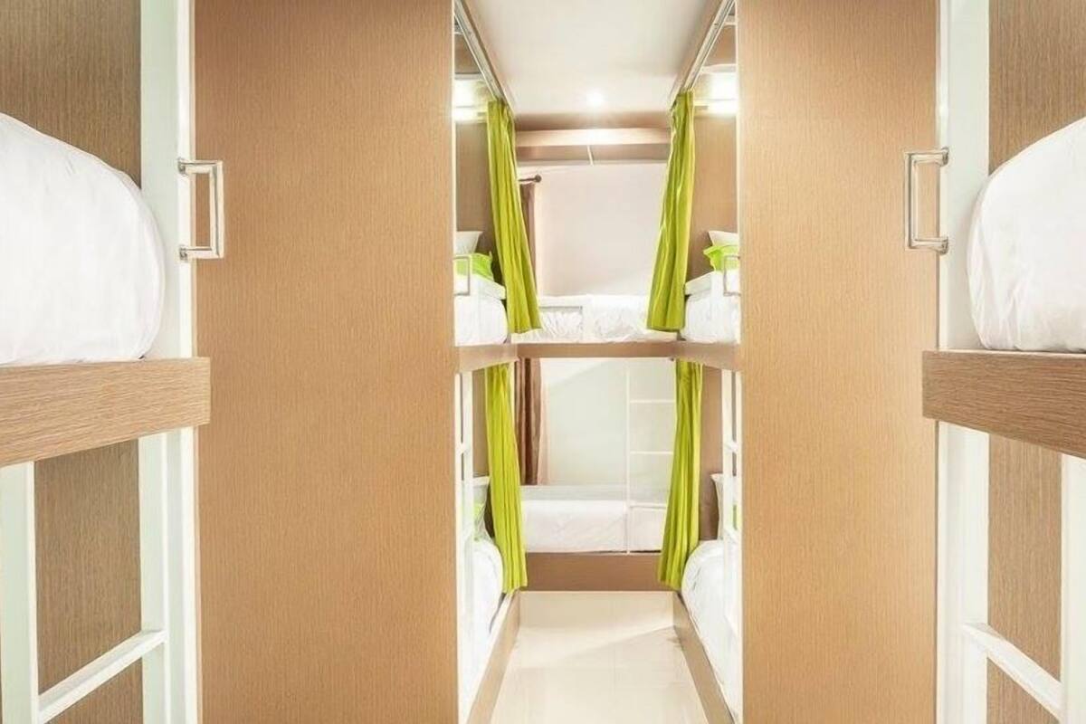 A narrow corridor with bunk beds on either side, leading to a bathroom with a shower and toilet.
