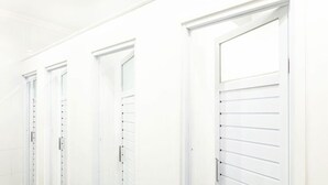 Una fila de puertas blancas con persianas horizontales, presumiblemente dando acceso a habitaciones de hotel.