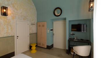 A room with a bed, a desk, a chair, a television, and a toilet.