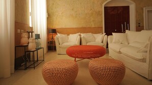 Una sala de estar con un sofá blanco, un reposapiés rojo y una mesita con velas.