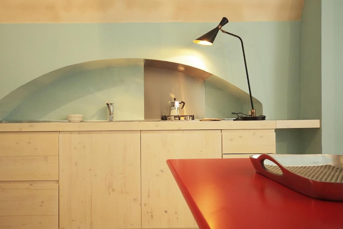 Une cuisine avec un plan de travail en bois, une machine à café et une chaise rouge.