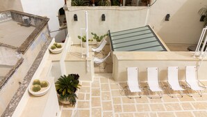 Una terraza en la azotea con piscina, sillones de descanso y plantas en macetas.