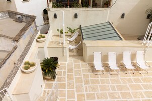 Une terrasse sur le toit avec une piscine, des chaises longues et des plantes en pot.
