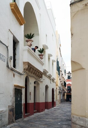 A narrow street with white buildings, some with balconies and potted plants. - Casa Galateo 20 (Gallipoli)