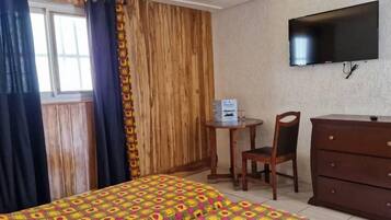 A room with a bed, a desk, a chair, a dresser, and a TV.