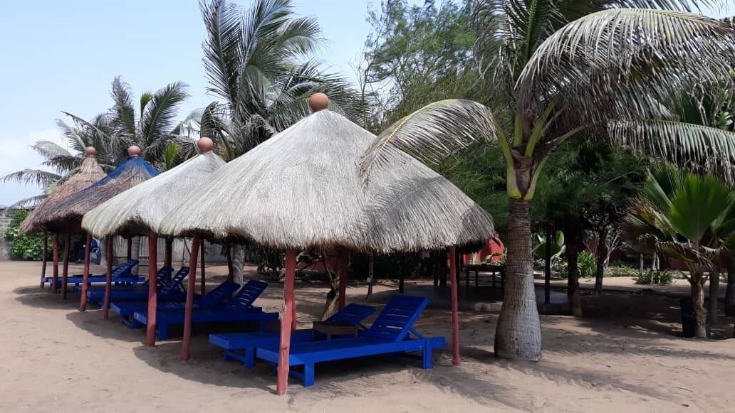 A beachside area with thatched umbrellas and blue lounge chairs.