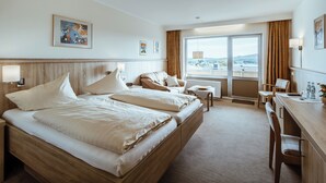 A hotel room with a large bed, a desk, and a view of the city. - Landgasthaus Pfahl (Wershofen)
