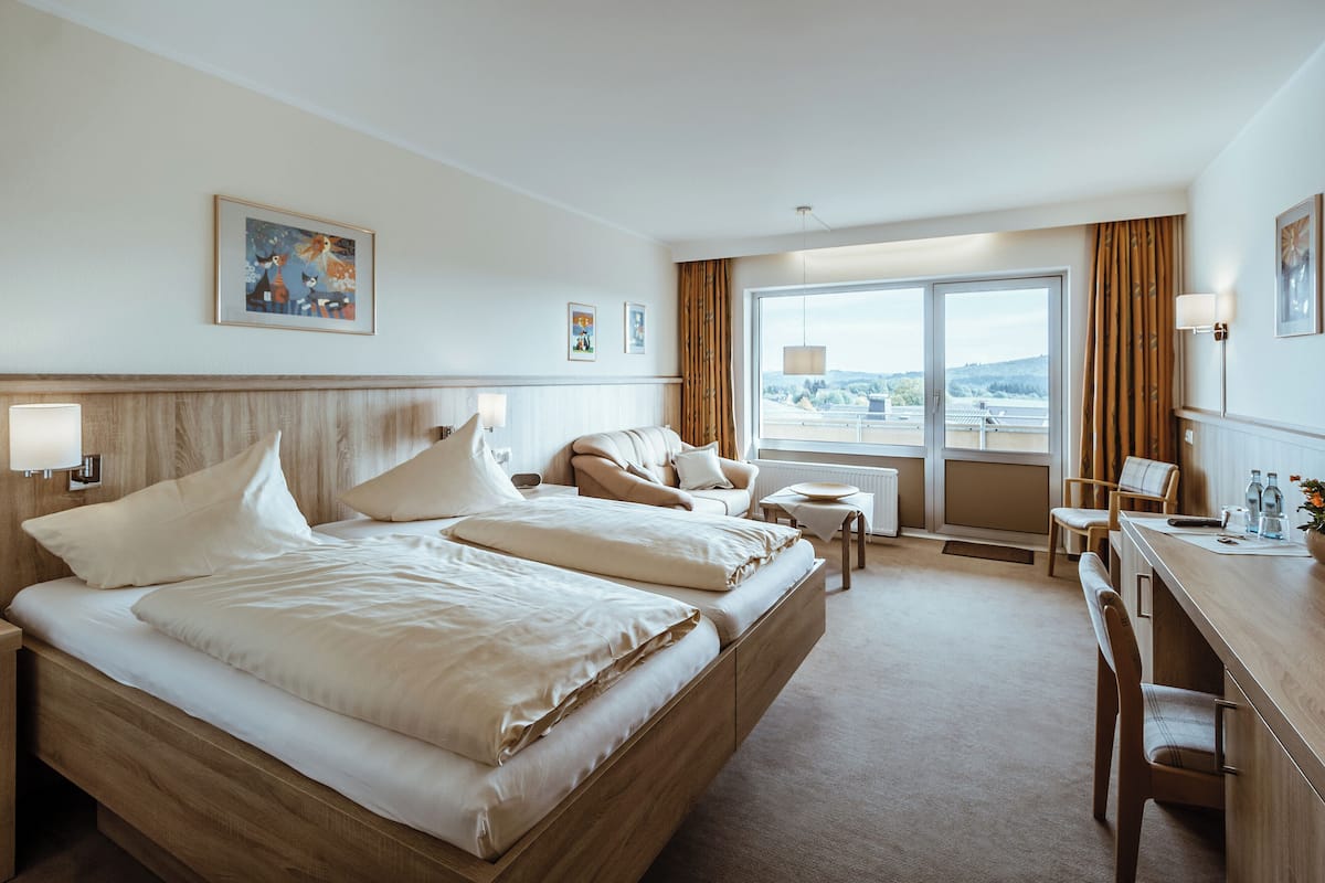Ein Hotelzimmer mit einem großen Bett, einem Schreibtisch und Blick auf die Stadt.