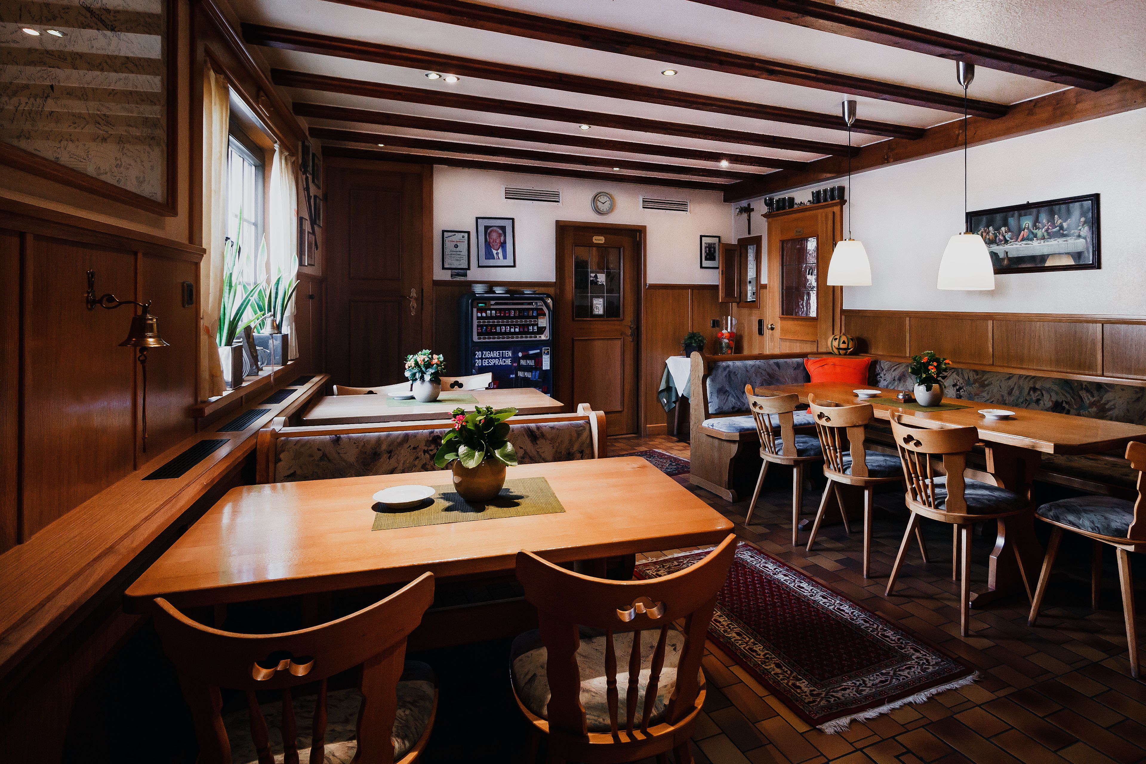 A cozy restaurant with wooden furniture, a large window, and a clock on the wall.