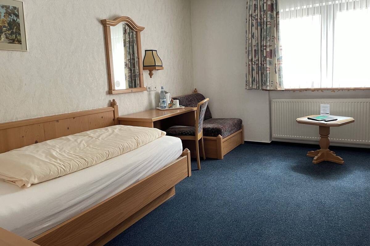 Ein Hotelzimmer mit Bett, Schreibtisch, Stuhl und kleinem Tisch.
