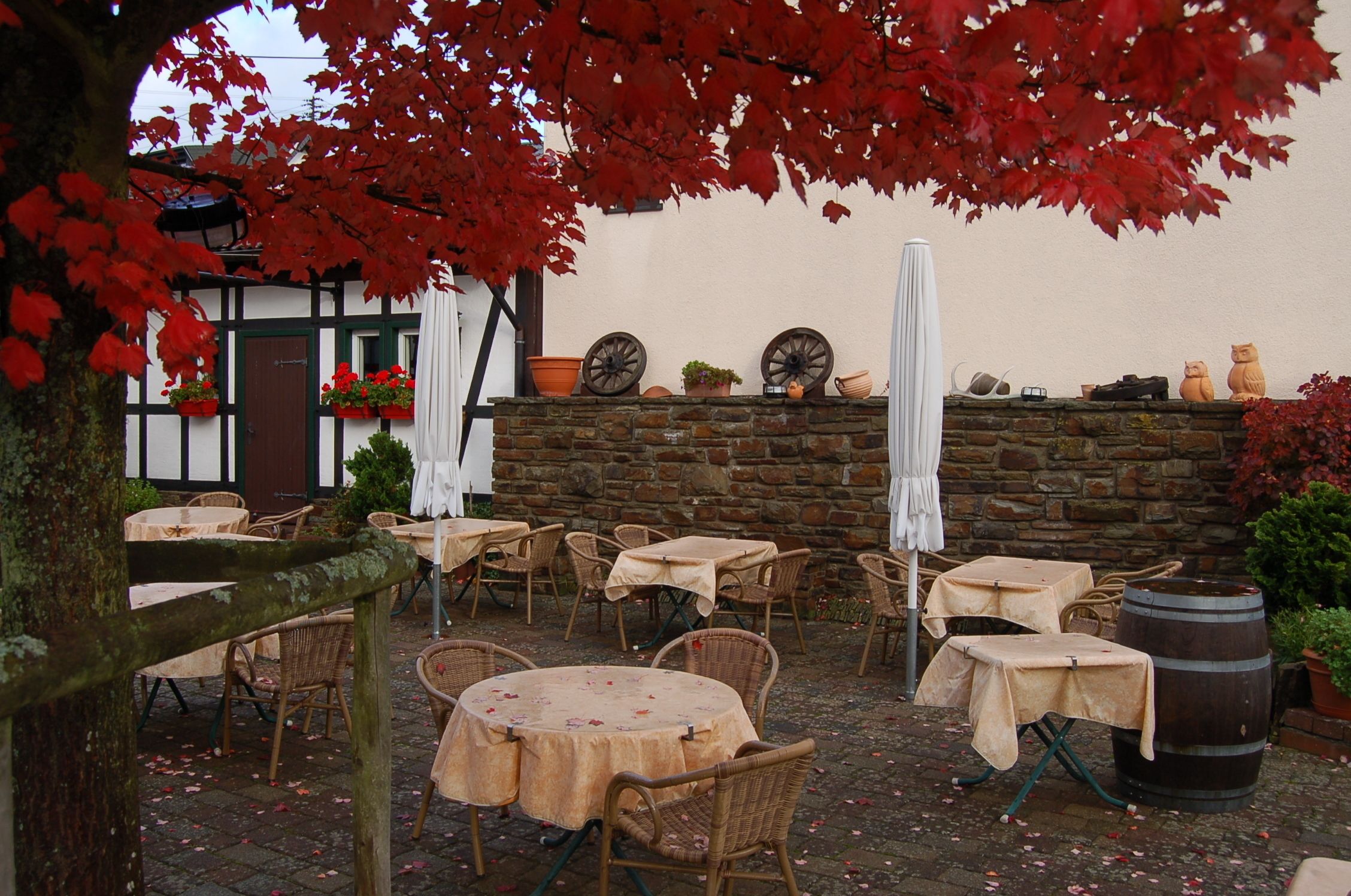 An outdoor seating area with tables and chairs, a stone wall, and potted plants.
