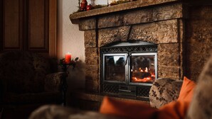 A cozy living room with a stone fireplace, a patterned sofa, and a decorative candle. - Landgasthaus Pfahl (Wershofen)