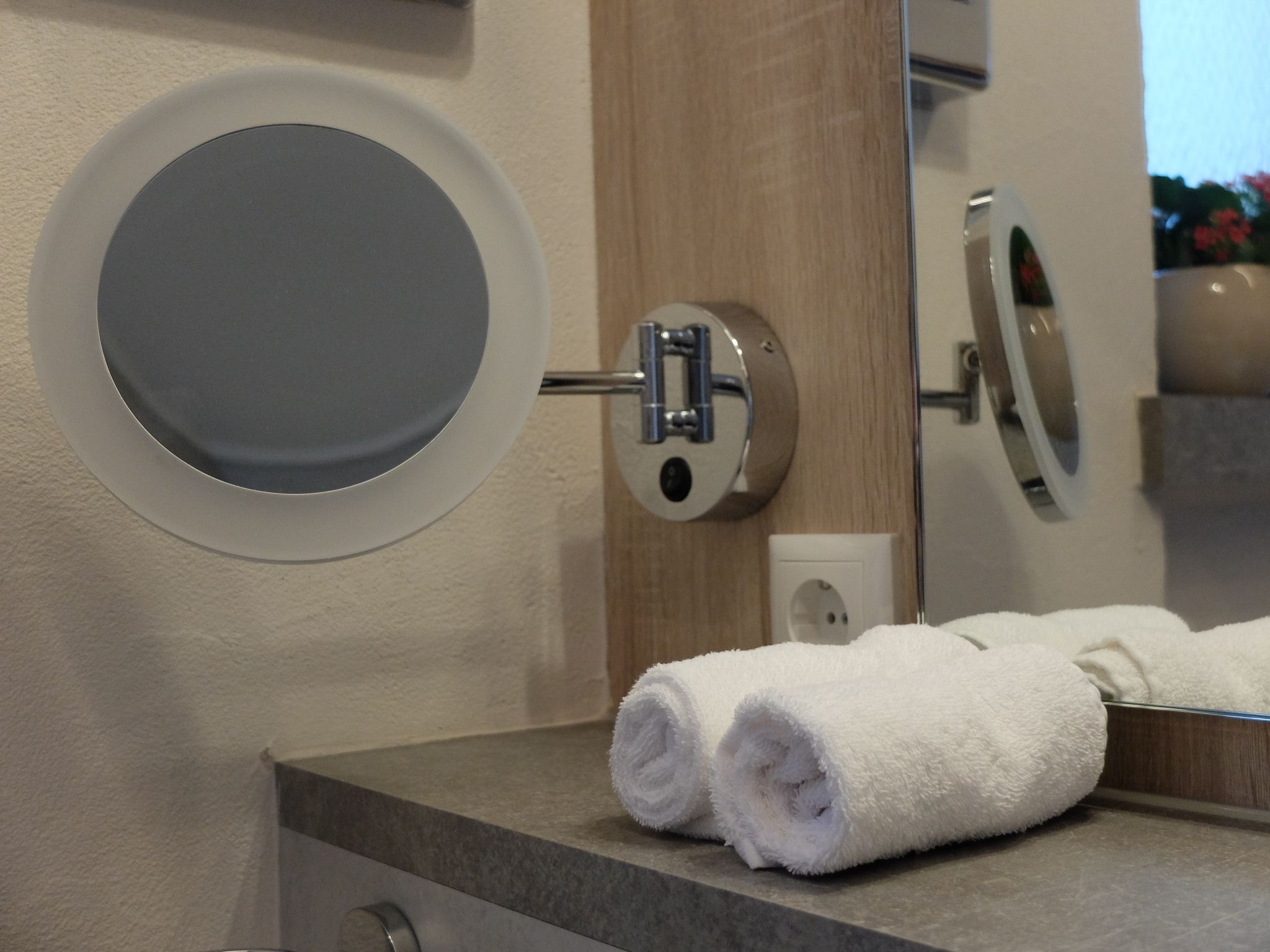 A bathroom with a round mirror, a towel rack, and a sink.