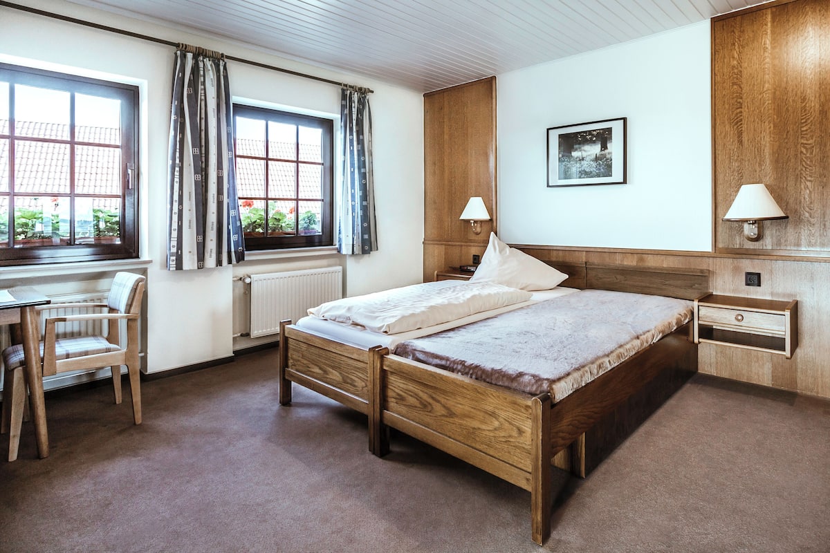 Ein Schlafzimmer mit einem hölzernen Bett, einem Schreibtisch und einem Stuhl.